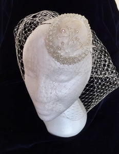 Satin pearl and feather bridal headpiece with birdcage.